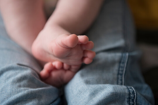 Feet of Caucasian baby boy on legs of mother