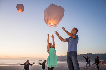 Caucasian father and daughter flying lantern balloon at beach