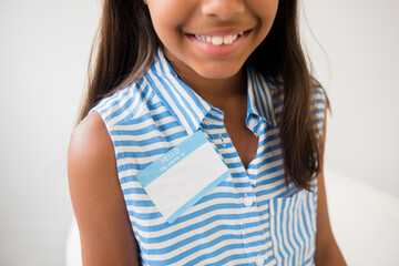 Smiling Mixed Race girl wearing name badge