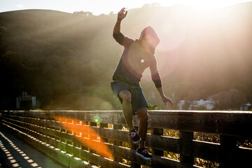 Mixed Race man jumping near railing on footbridge