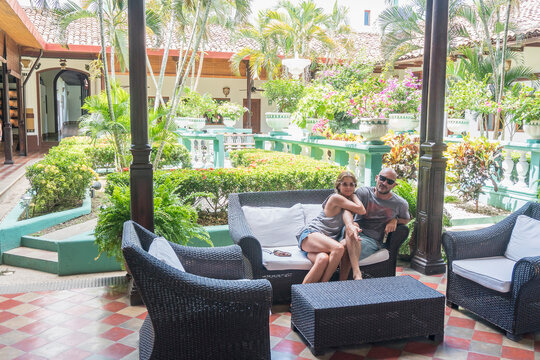 Smiling Caucasian couple on sofa in hotel courtyard