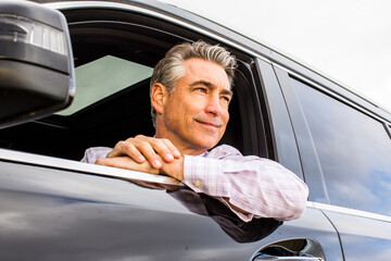 Smiling Caucasian businessman leaning on car window