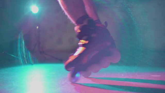 Guy spinning on roller skates on spotlight in dark place. Teenager showing skills on freeskate. Young male example of active nightlife youth culture. Concept of extreme, lifestyle, sport.