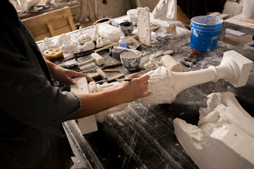 Hands of Caucasian sculptor carving plaster piece
