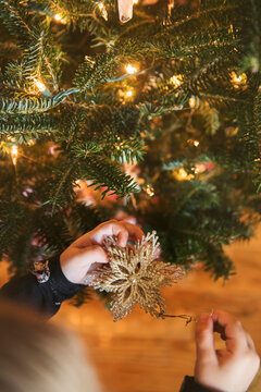 Caucasian girl hanging star ornament on Christmas tree