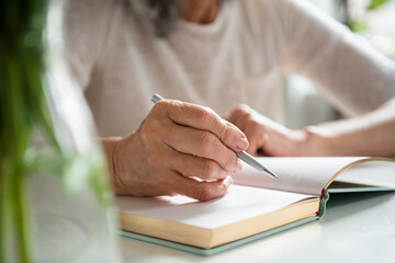 Hands of older woman writing in journal