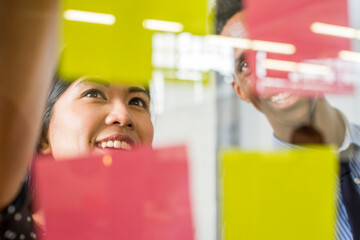 Woman and man reading adhesive notes in office