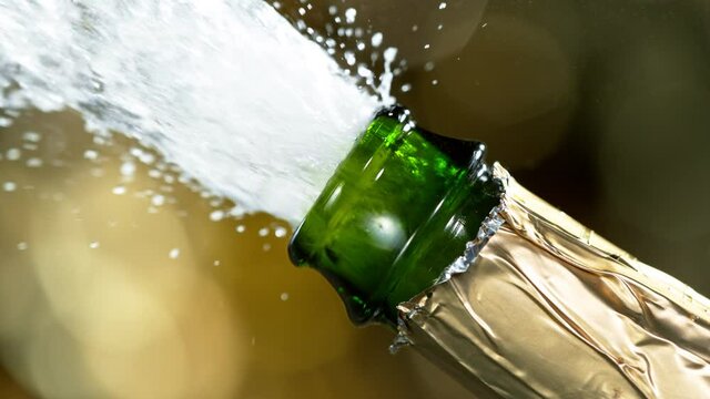 Super slow motion of Champagne explosion with flying cork closure, opening champagne bottle closeup.