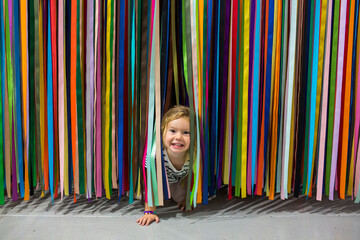 Caucasian girl crawling under colorful hanging streamers
