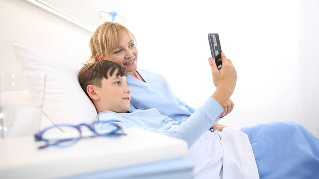 nurse takes care of a child in the hospital by taking selfies with the mobile phone lying on the bed
