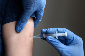 Doctor holds syringe and makes COVID-19 vaccine injection to patient arm