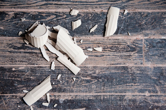 Broken shards of cup on wooden floor
