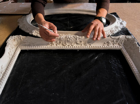 Hands of Caucasian man detailing picture frame