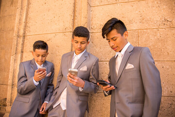 Hispanic boys wearing suits texting on cell phones