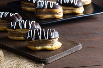 Eclairs with black chocolate and white chocolate with custard on rustic table. Traditional French dessert. Eclair Pastery concept