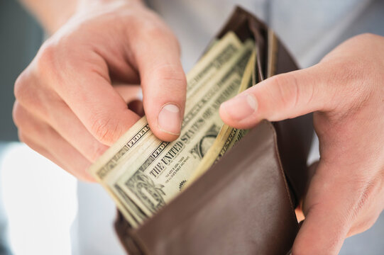 Young man holding wallet and counting money