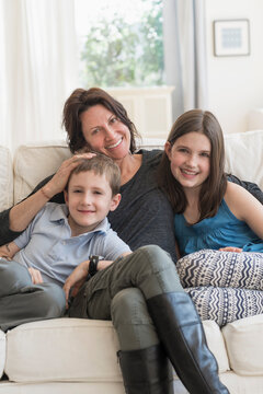 Mother and kids(8-9, 10-11) sitting on sofa