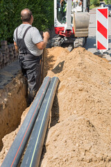 Workers installing optical fibre cables in shallow trenches.