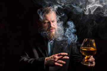 Solid confident bearded man in suit with glass of whisky and cigar with fume