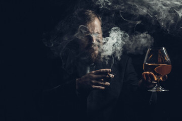 Solid confident bearded man in suit with glass of whisky and cigar with fume