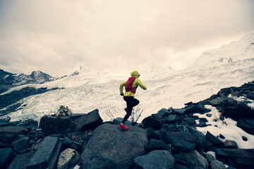 Woman trail runner cross country running on high altitude mountain ridge