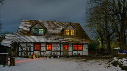 Illuminated timbered farm house on a snowy winter evening