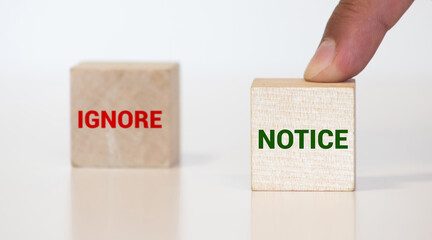 IGNORE versus NOTICE directional signs on wooden block, Choice concept image