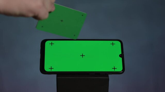 Online shopping concept. Smartphone green screen with traking points with green credit card with tracking dots moving camera on black background.