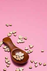 Naklejka premium Pink background with plywood hearts and a wooden spice spoon. Place for text. Valentine's Day concept.