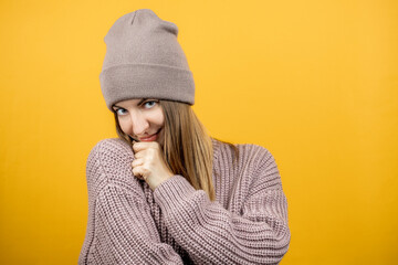 funny caucasian young woman showing feel shy facial over yellow background. isolated yellow background. person warm dressed
