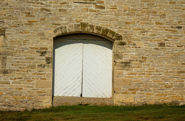 Fototapeta na wymiar White wood doors on stone building.