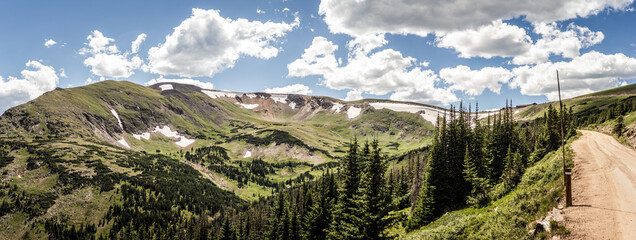Panorama shot of green hill with remnants of snow in Rocky mountains national park in america