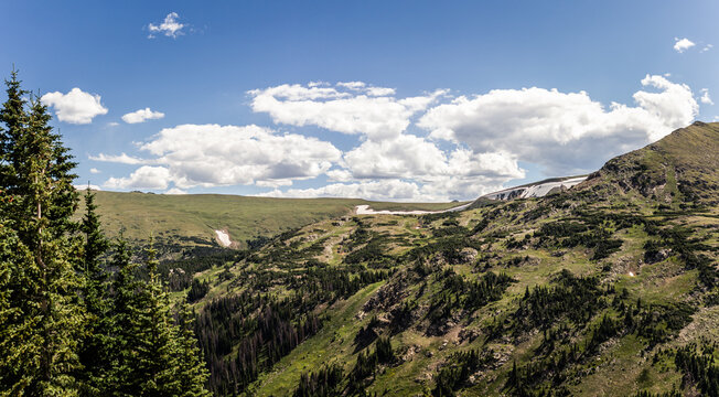 Panorama shot of green hill with remnants of snow in Rocky mountains national park in america