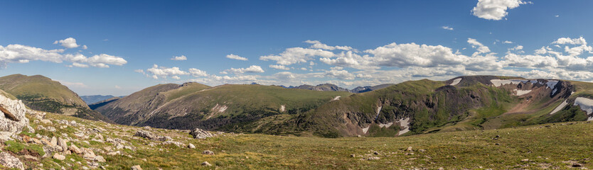 Fototapeta na wymiar Panorama shot of green valley with remnants of snow in Rocky mountains antional park in america