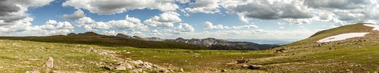 Obraz na płótnie Canvas Panorama shot of green hill with remnants of snow in Rocky mountains national park in america