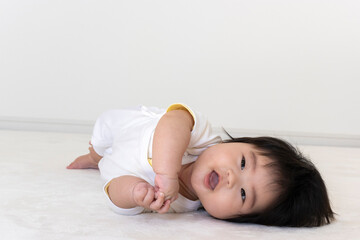 Obraz na płótnie Canvas 寝返り途中でカメラ目線の赤ちゃん(0歳、生後5か月、女の子)