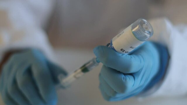 Concept of Covid 19 vaccine vaccinating, development and creation, doctor or scientist in laboratory holding a single dose of  2019-ncov vaccine, a syringe and ampule with SARS-CoV-2 vaccination