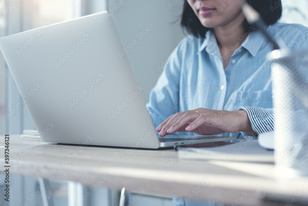 Wall mural woman typing on laptop computer surfing the internet and online working in office