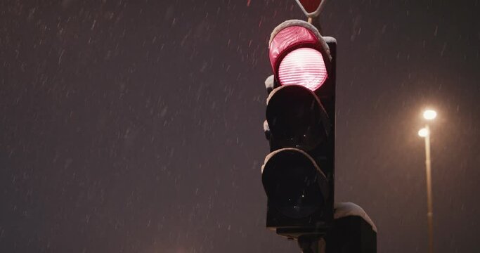 Traffic light turn red yellow green on a cold winter night snowfall
