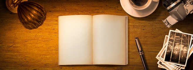 アンティークな木製テーブルの上にある空白のノートブック、コーヒーカップ、万年筆、モノクロ写真。趣味人の書斎のイメージ