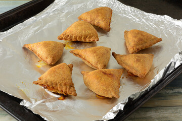 Hot out of the oven baked samosa snacks or appetizers on aluminum foil on baking sheet