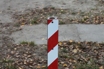 one red white striped iron fence post outdoors on gray brown background