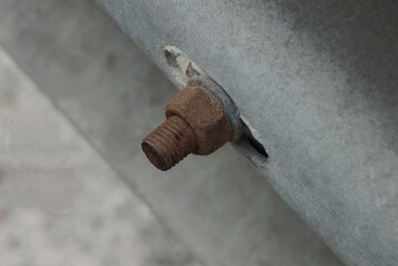 one old brown rusty bolt with a twisted nut on a gray metal wall