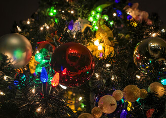 Close up of decorations on Christmas trees with ornaments, balls, coloured lights