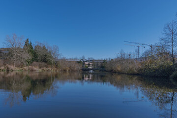 Obraz premium 2020-12-04 A SMALL LAKE WITH A REFLECTION OF NEARBY CRANES AND A BRIGHT BLUE SKY.
