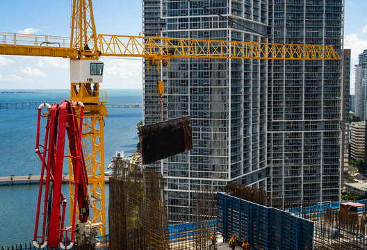 Crane lowering metal mold for formwork in preparation of pouring concrete at downtown Miami high rise skyscraper construction project 