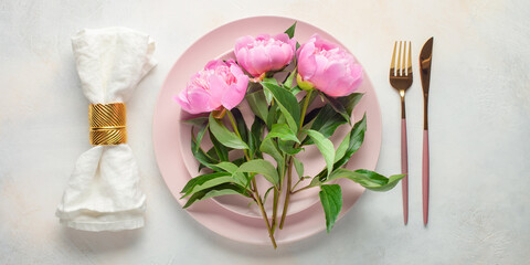 Fototapeta na wymiar Pink peony flowers and a plate with cutlery on the table. Top view. Flat lay
