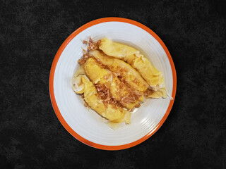 Delicious egg Roll on white dish, Thai food Style Omelette on black background