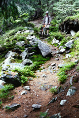 Fototapeta premium Young caucasian cyclist on a mountain bike rides along mountain trails in a mountain forest.