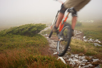 Blurred in motion mountain biker drives down from the mountain peaks